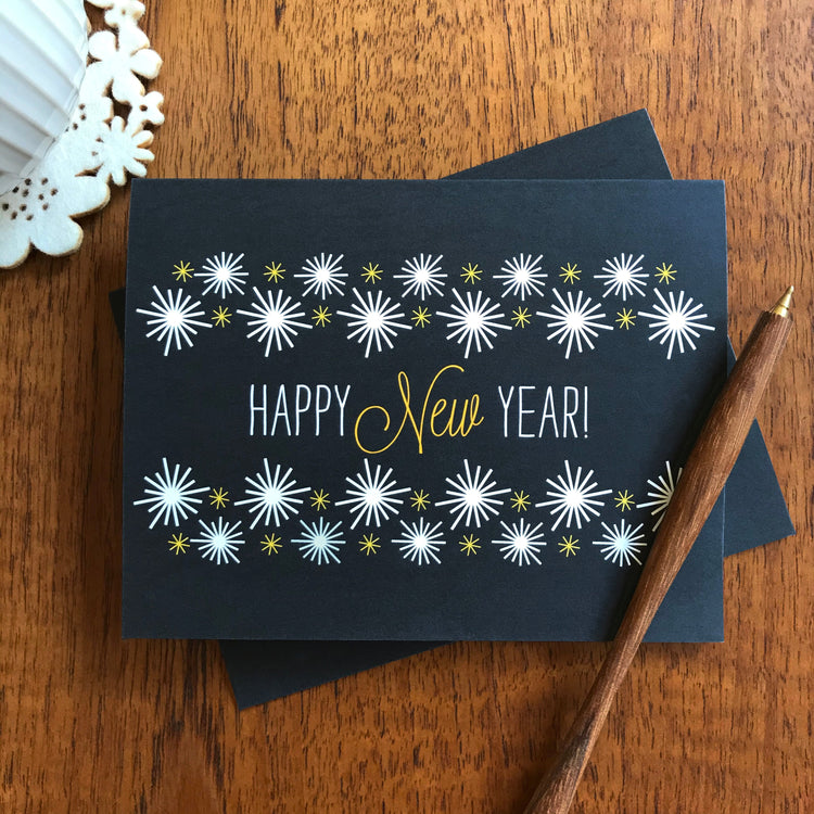 Black New Years greeting card with white and yellow star bursts.
