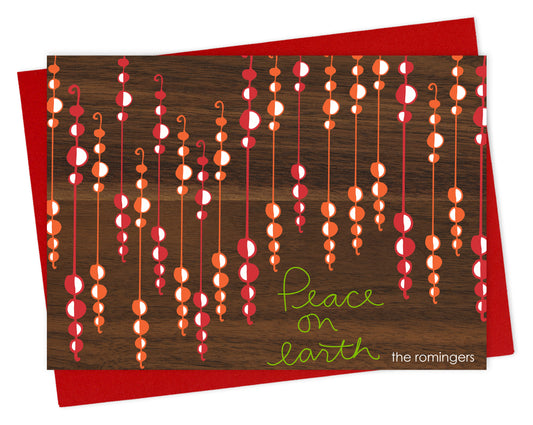Customizable paper holiday card featuring festive beaded garlands with “Peace on Earth” text on a printed walnut wood grain background. Shown with a red envelope.