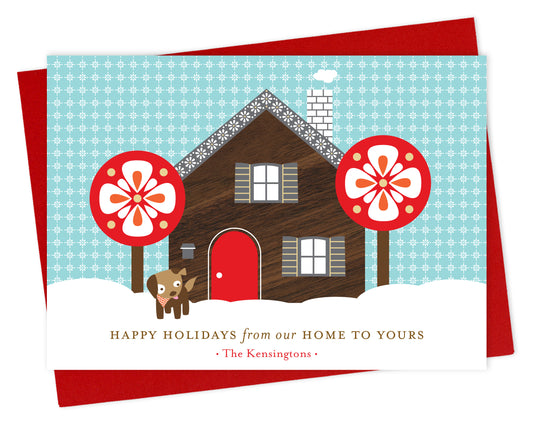 Customizable paper holiday card with a printed walnut wood grain house, dog, snowy sky, "Happy Holidays from our Home to Yours" text and a personal greeting. Shown with a red envelope.