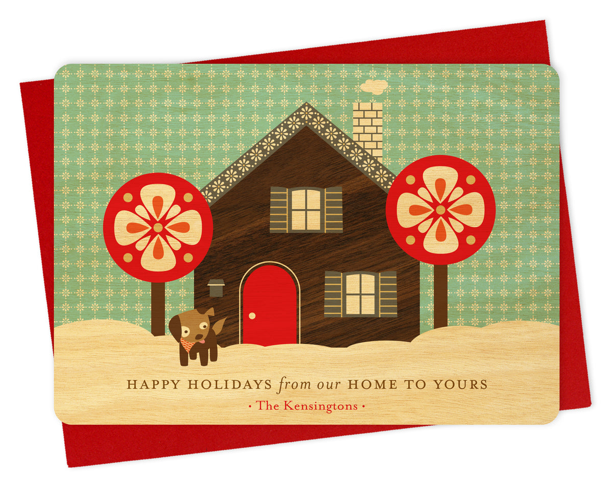 Customizable birch wood holiday card with a printed walnut wood grain house, dog, snowy sky, "Happy Holidays from our Home to Yours" text and a personal greeting. Shown with a red envelope.