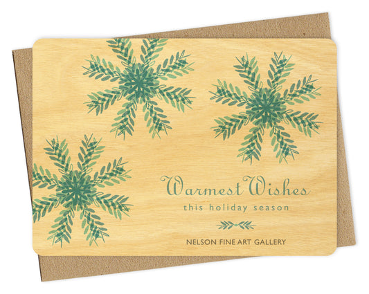 Customizable wood holiday card featuring blue snowflakes on a birch wood background with space for a logo and/or personal message. Shown with a kraft envelope.