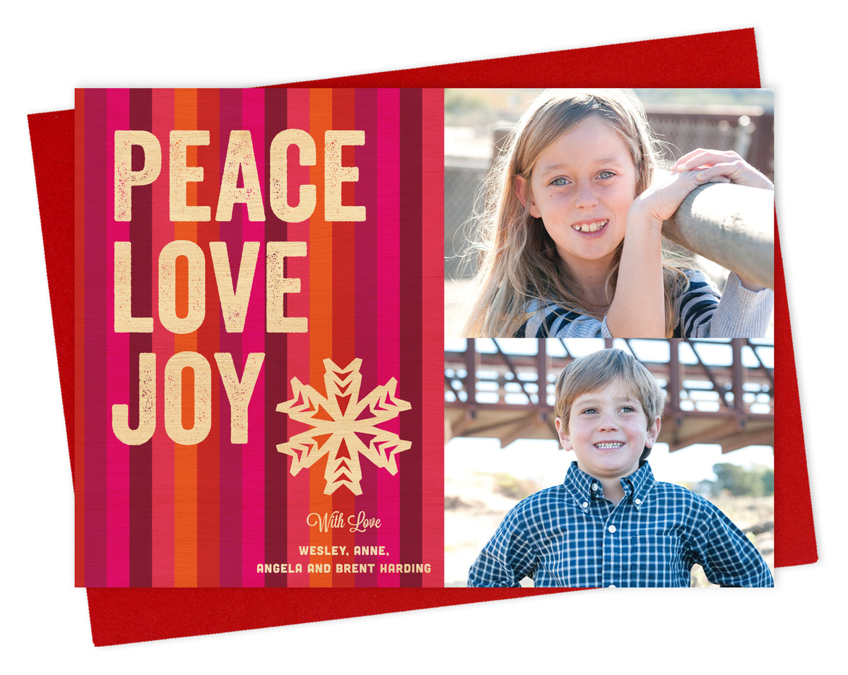 Customizable paper holiday card featuring 2 photos on the right and colorful vertical stripes with “PEACE LOVE JOY” text, a snowflake and a personal greeting on the left. Shown with a red envelope.