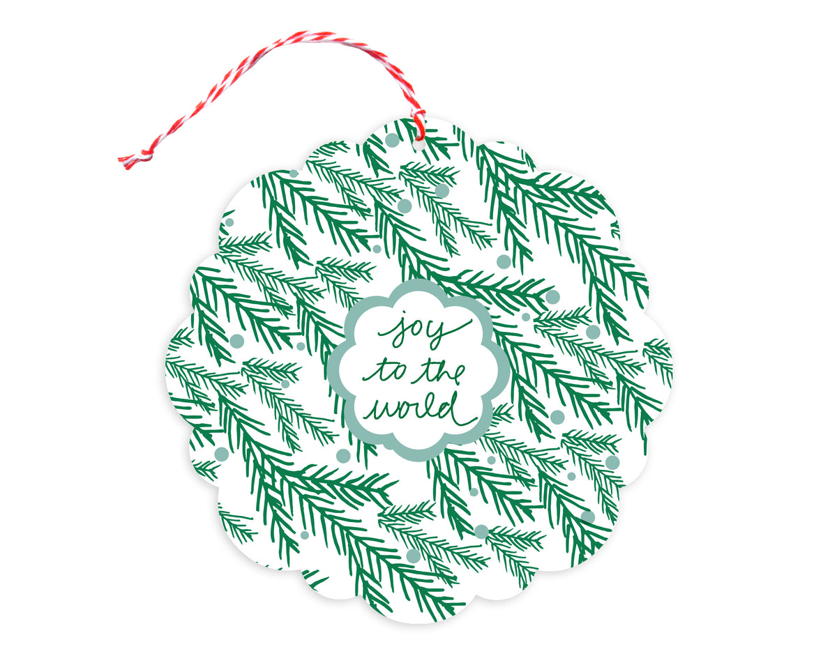 Front of customizable paper holiday ornament card with festive evergreen sprigs and "Joy to the World" text on a white background. Round ornament with scalloped edges.