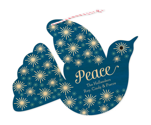 Front of dove-shaped paper personalized holiday ornament card with 'Peace' text, a personal greeting and a star pattern on a blue and printed birch wood grain background.