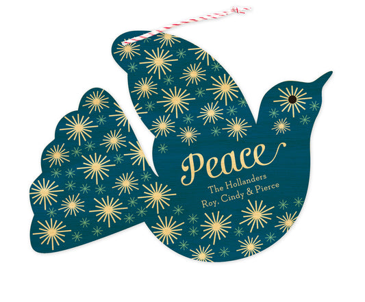 Front of dove-shaped wood personalized holiday ornament card with 'Peace' text, a personal greeting and a star pattern on a blue background.