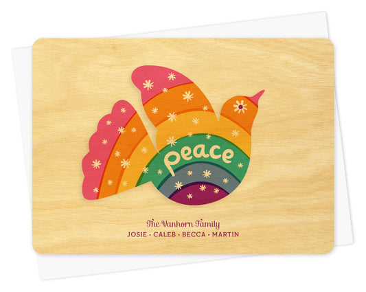 Customizable birch wood holiday card with colorful dove, “Peace” sentiment and personal greeting. Shown with a white envelope.