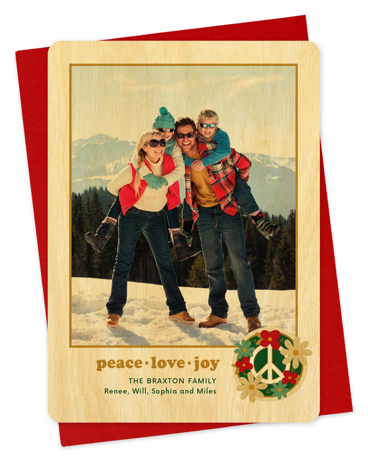 Customizable wood holiday card featuring a family photo with “peace love joy” text and a peace sign surrounded by flowers near the bottom, shown with a red envelope.