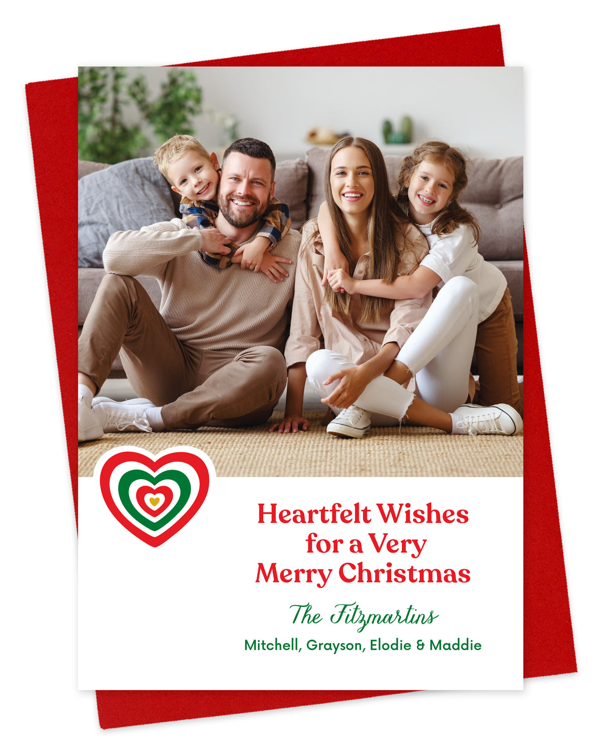 Customizable paper holiday card featuring a family photo, a red and green heart, 'Heartfelt Wishes for a Very Merry Christmas' text and a personal greeting. Shown on a red envelope.