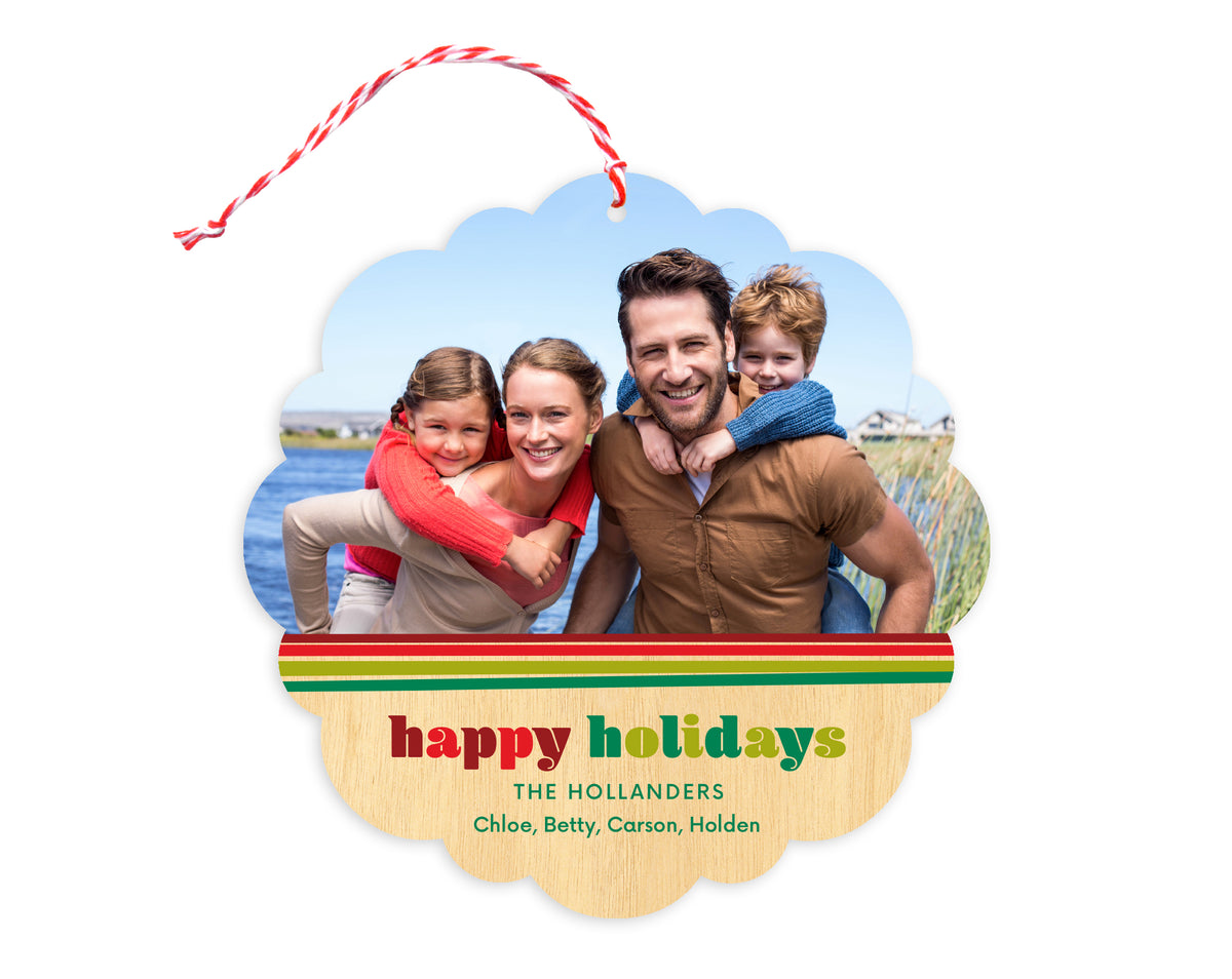 Front of customizable paper holiday ornament card featuring a photo with a festive red and green striped border, “Happy Holidays" text and a personal message on a printed birch wood background. Round ornament with scalloped edges.