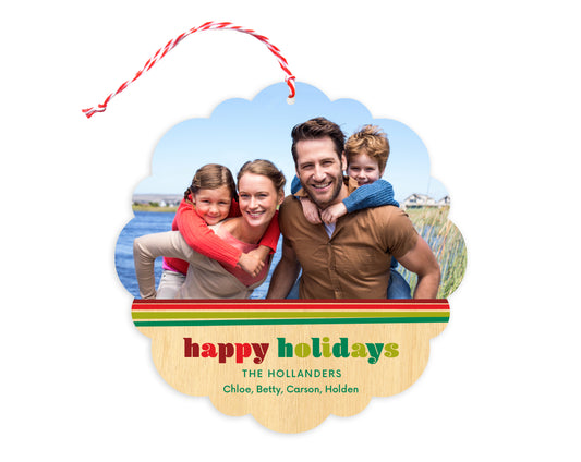 Front of customizable paper holiday ornament card featuring a photo with a festive red and green striped border, “Happy Holidays" text and a personal message on a printed birch wood background. Round ornament with scalloped edges.