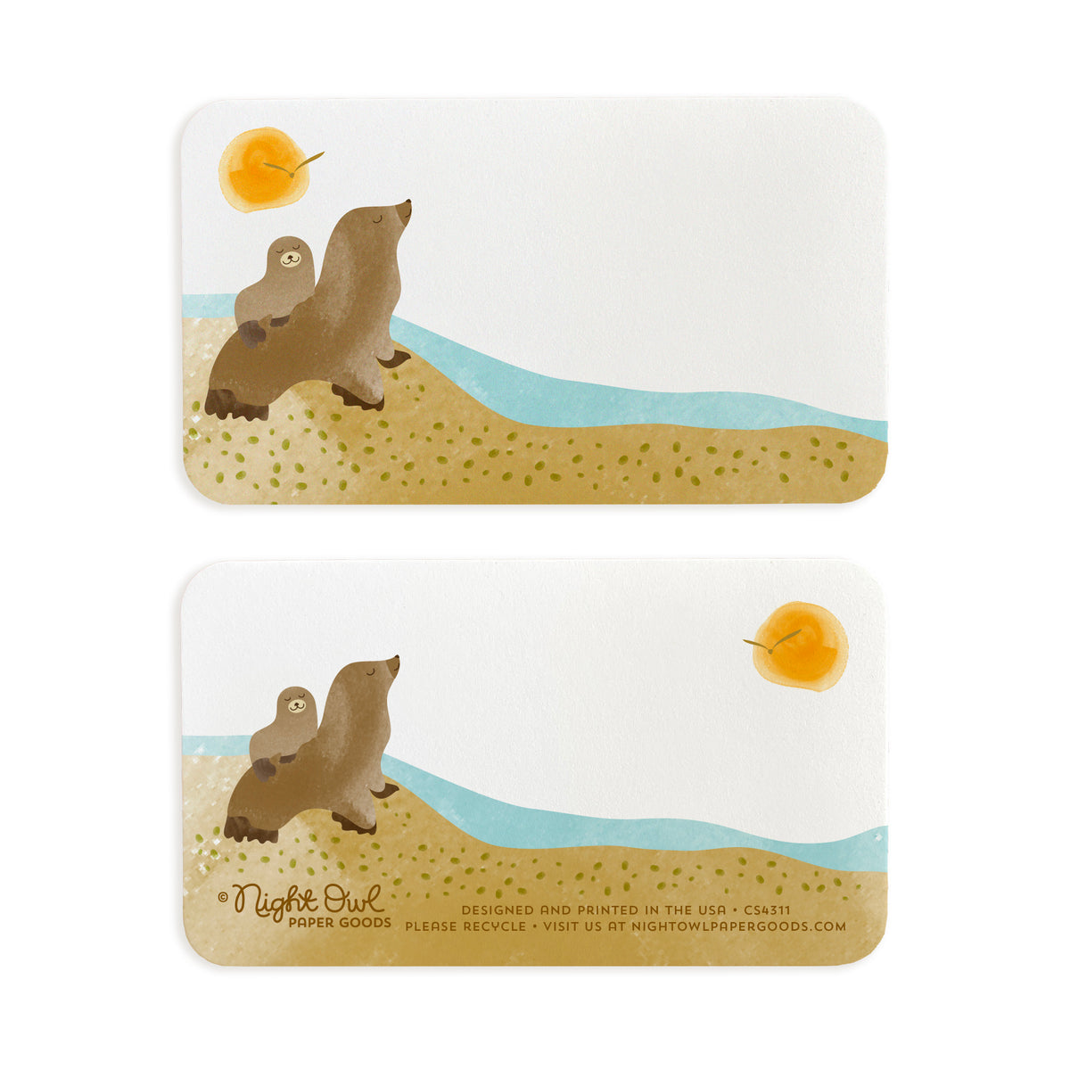 A small white Sea Lions note card shown front and back. The front features cute sea lions on a sandy beach beside blue ocean water with a golden sun overhead, while the back has a coordinating sea lion design and small text at the bottom that reads "Night Owl Paper Goods - Designed and printed in the USA - Please recycle - Visit us at nightowlpapergoods.mom." Both sides include space for a handwritten note.