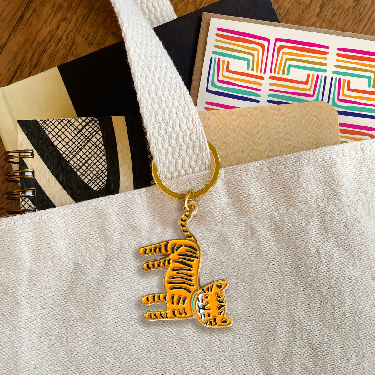 Tiger enamel keychain hanging from a tote bag handle