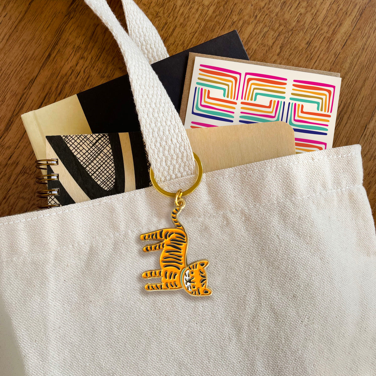 Tiger enamel keychain hanging from a tote bag handle