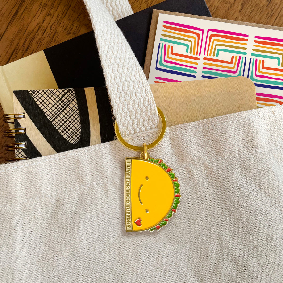 Taco Tuesday enamel keychain hanging from a tote bag handle