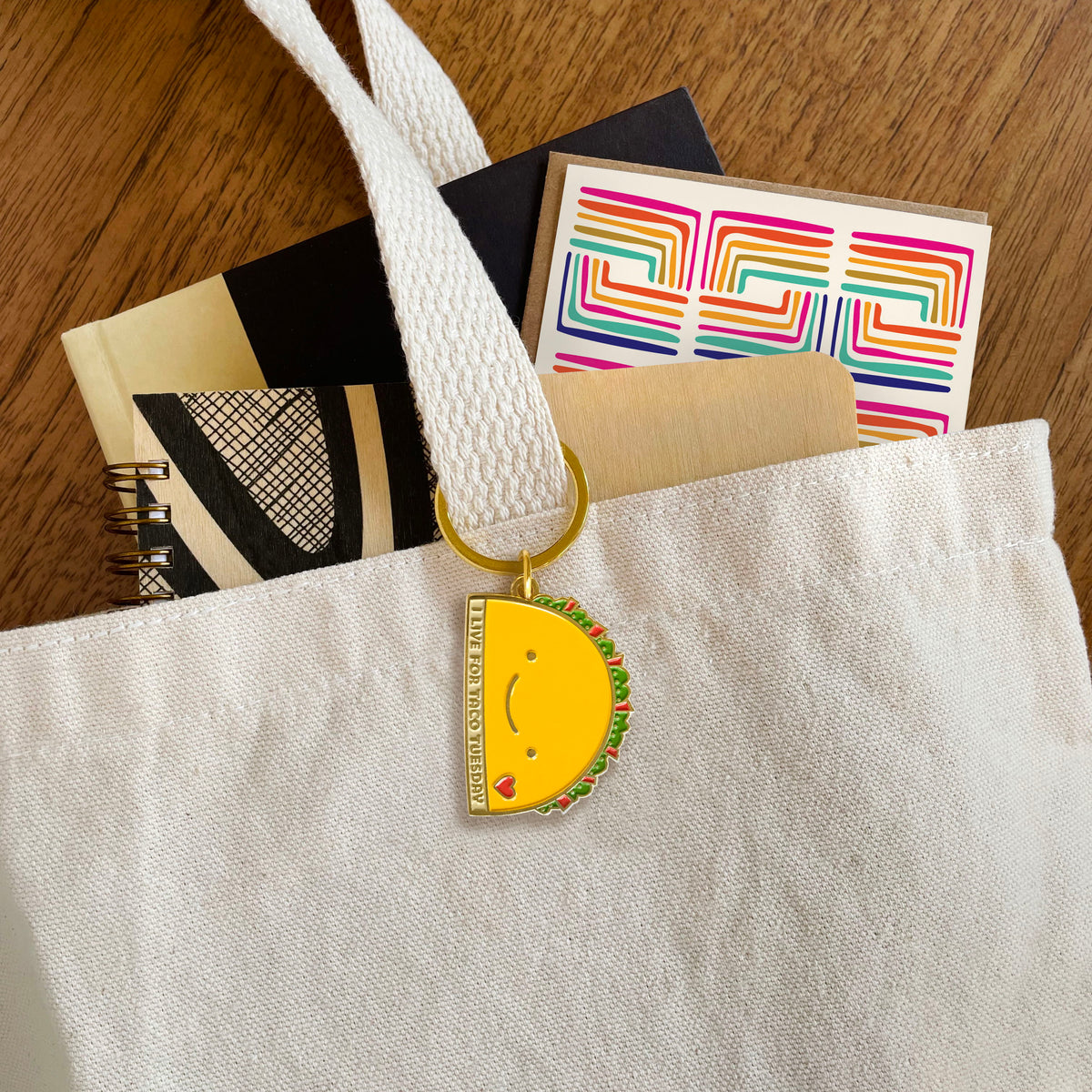Taco Tuesday enamel keychain hanging from a tote bag handle