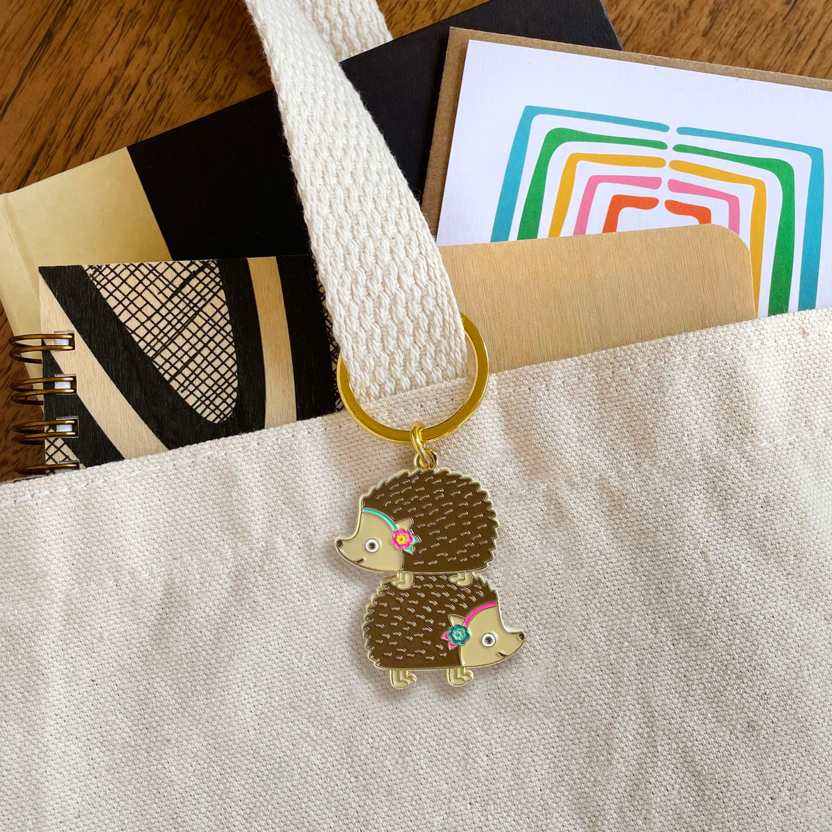 Stacked Hedgehogs enamel keychain hanging from a tote bag handle