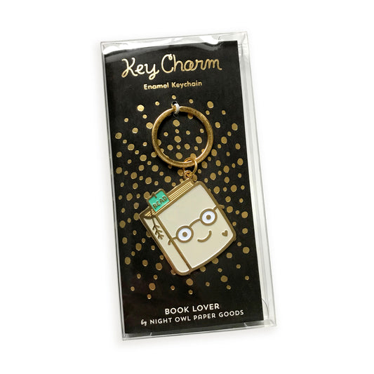 Book Lover enamel keychain on gold foil stamped backer card packaged in a clear gift box. Black backer card reads "Key Charm Enamel Keychain" at top and "Book Lover by Night Owl Paper Goods" at bottom.
