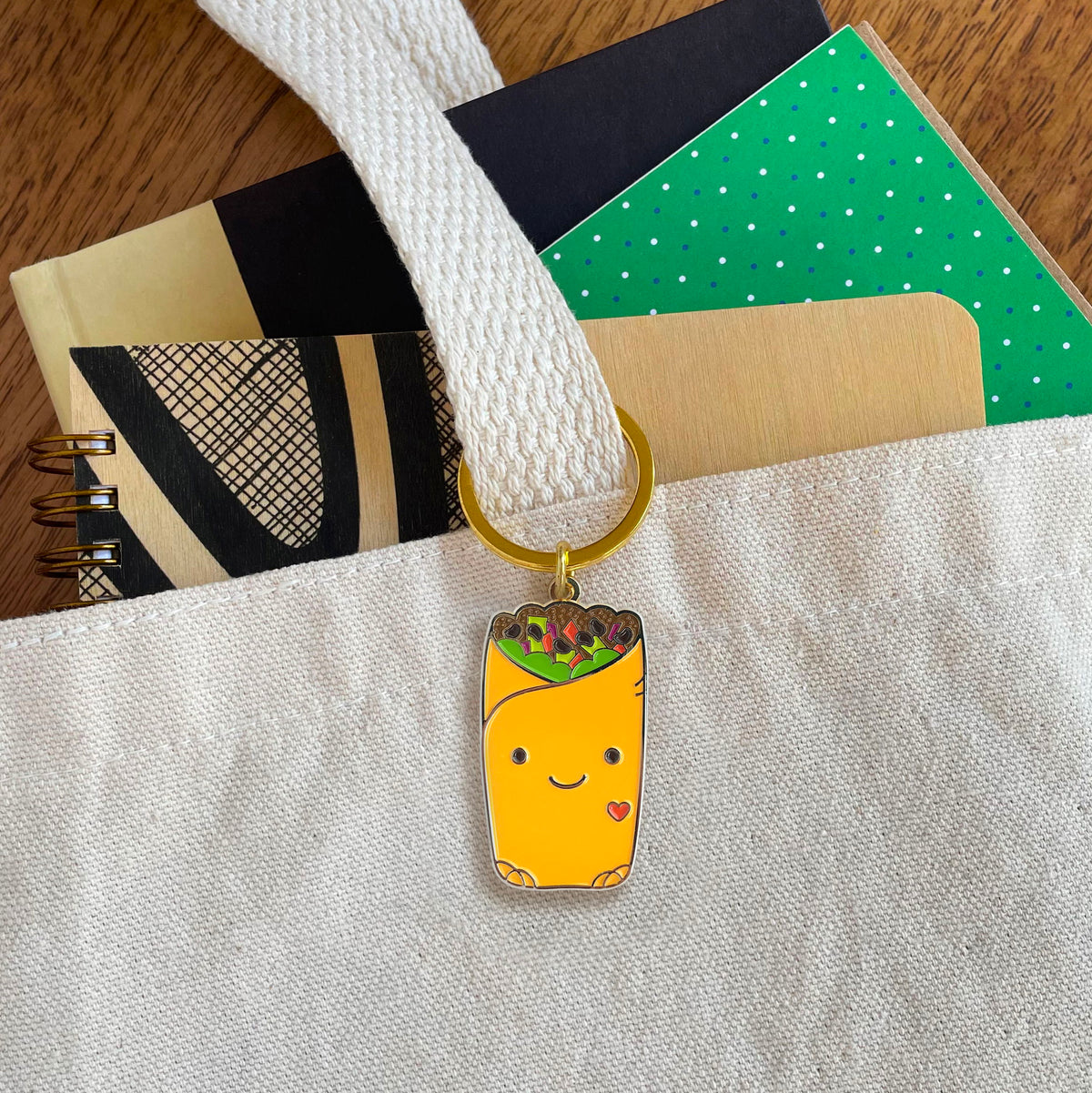 Burrito enamel keychain hanging from a tote bag handle