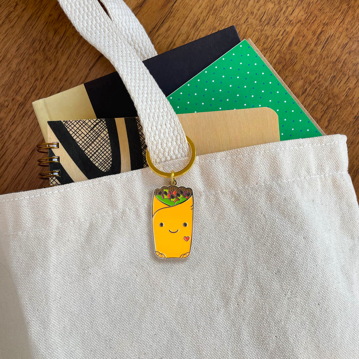 Burrito enamel keychain hanging from a tote bag