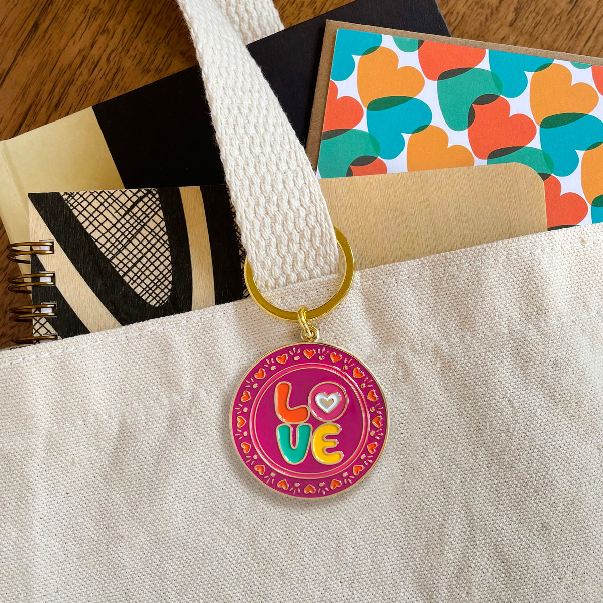 Love enamel keychain hanging from a tote bag handle