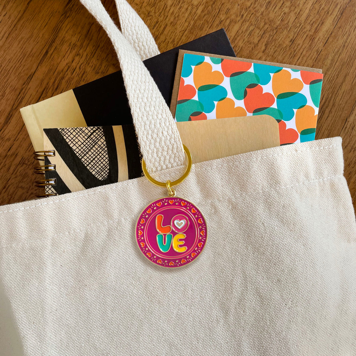 Love enamel keychain hanging from a tote bag