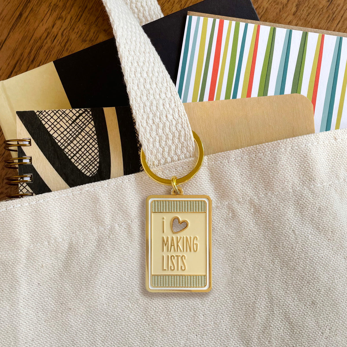 Making Lists enamel keychain hanging from a canvas tote bag handle