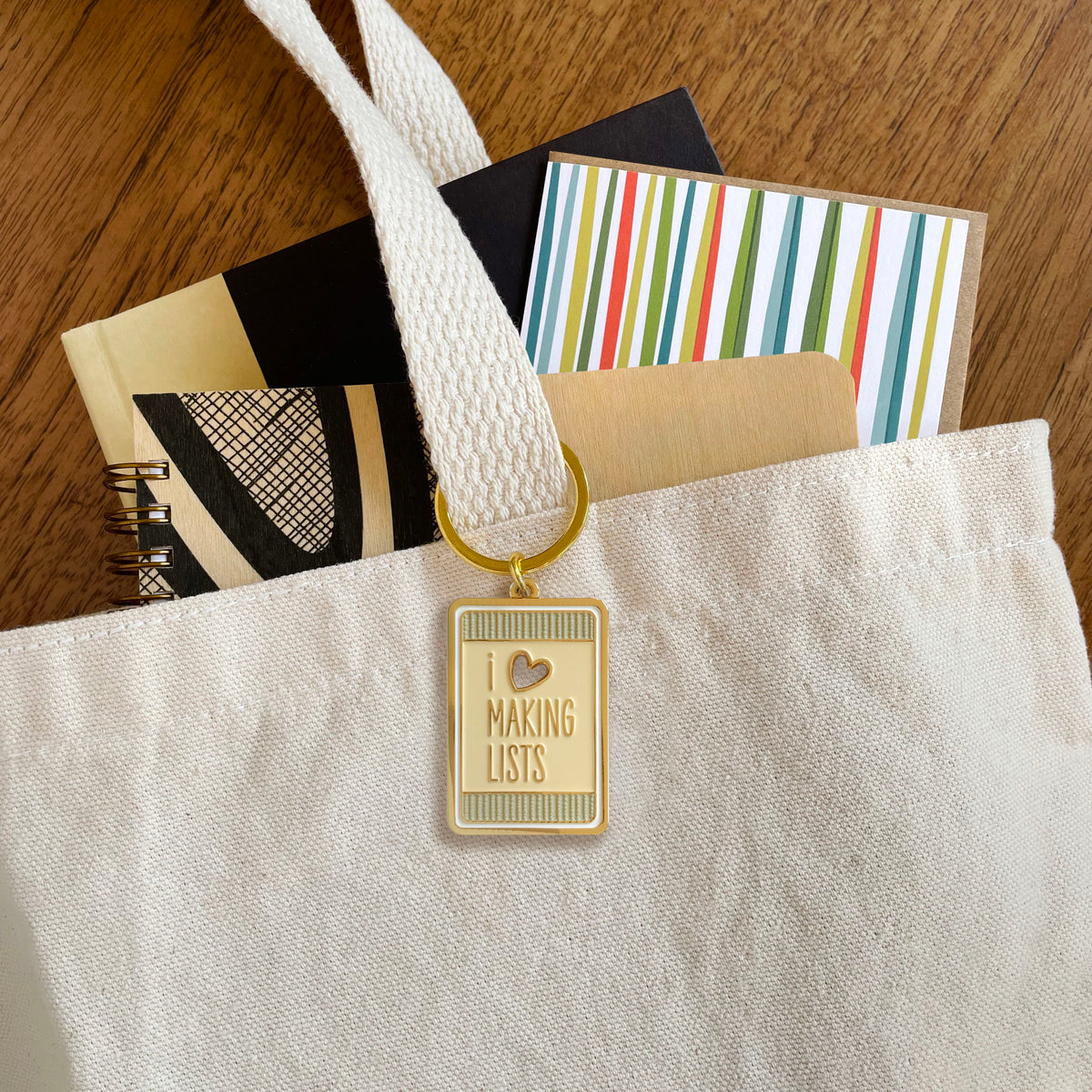 Making Lists enamel keychain hanging from a canvas tote bag handle