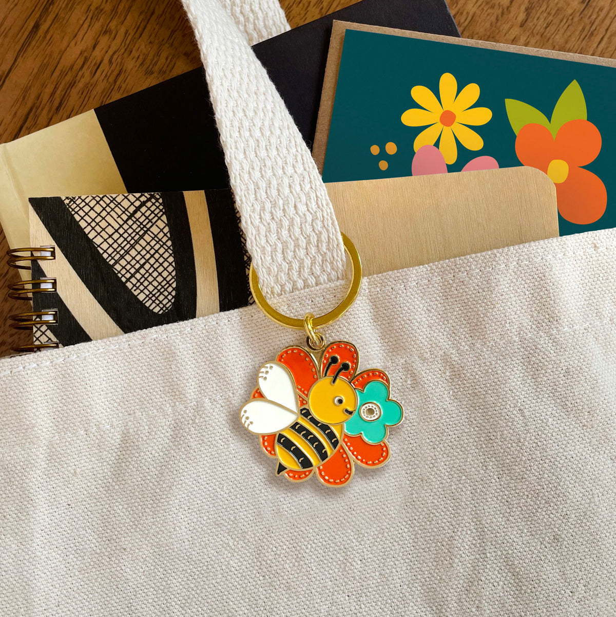 Bumble Bee enamel keychain hanging from a canvas tote bag handle