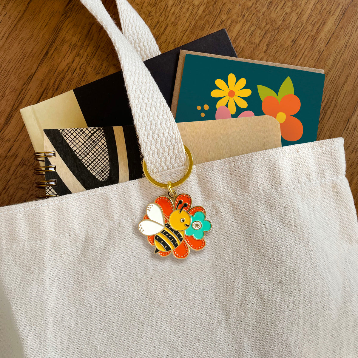 Bumble Bee enamel keychain hanging from a canvas tote bag handle