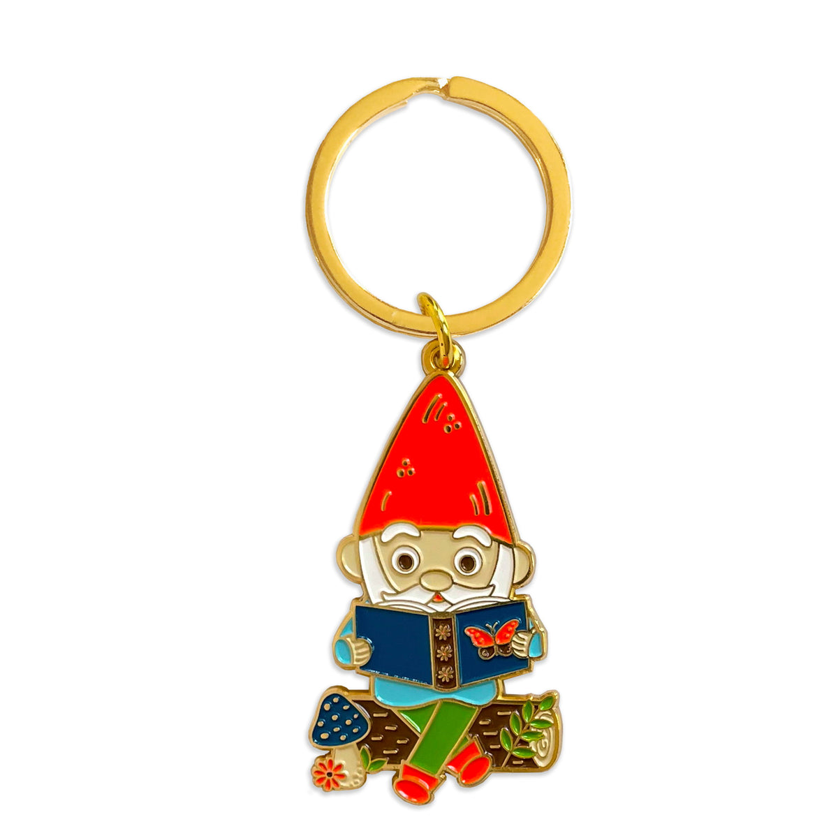 Gold metal keychain of a gnome sitting on a log, reading a book, on a gold key ring