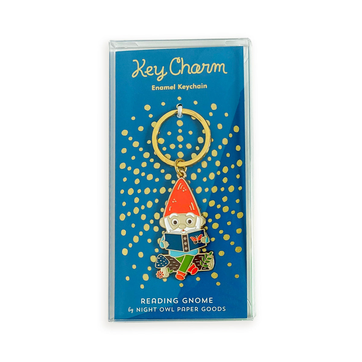 Reading Gnome enamel keychain on gold foil stamped backer card packaged in a clear gift box. Blue backer card reads "Key Charm Enamel Keychain" at top and "Reading Gnome by Night Owl Paper Goods" at bottom.

