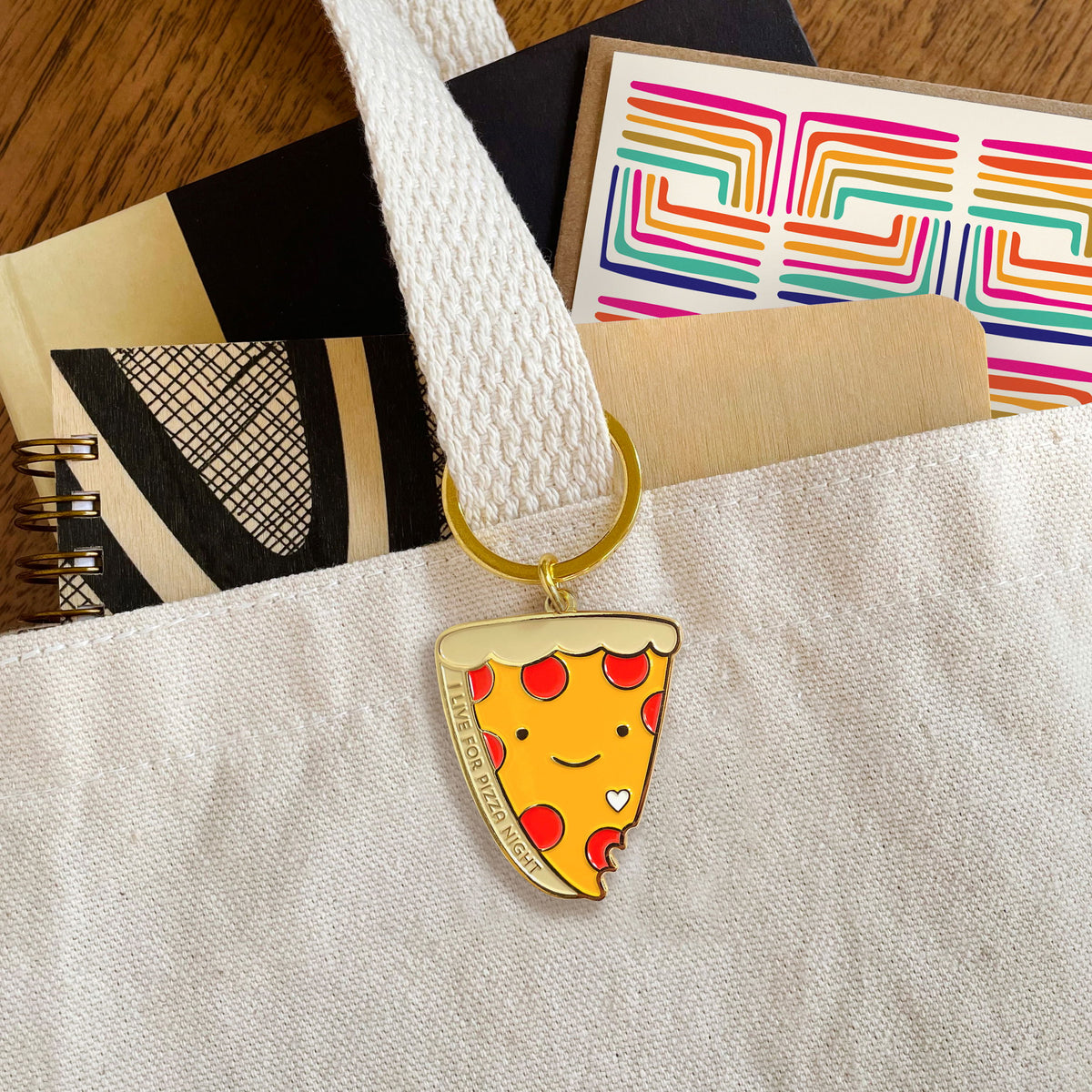 Pizza Night enamel keychain hanging from a canvas tote bag handle
