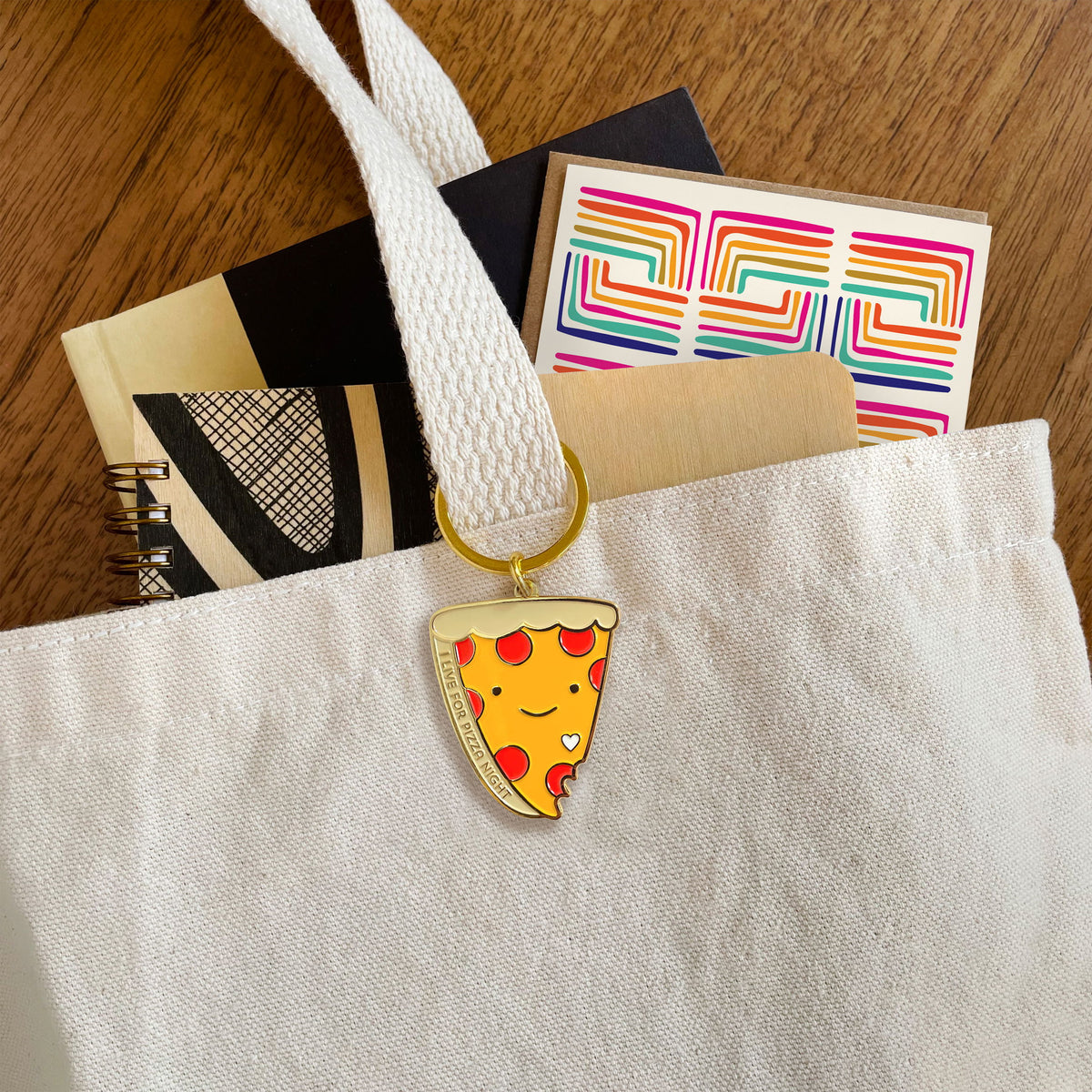 Pizza Night enamel keychain hanging from a canvas tote bag handle