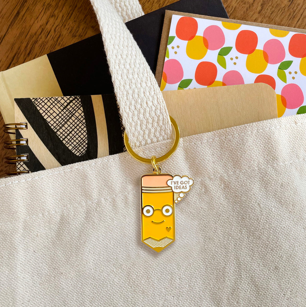 Idea Pencil keychain hanging from a canvas tote bag handle