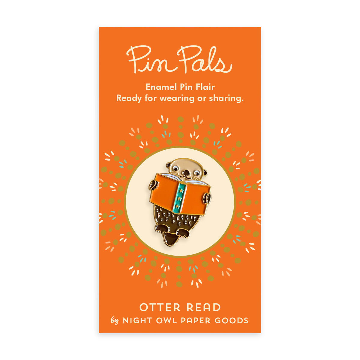 Enamel pin of an otter reading a book mounted on an orange backer card