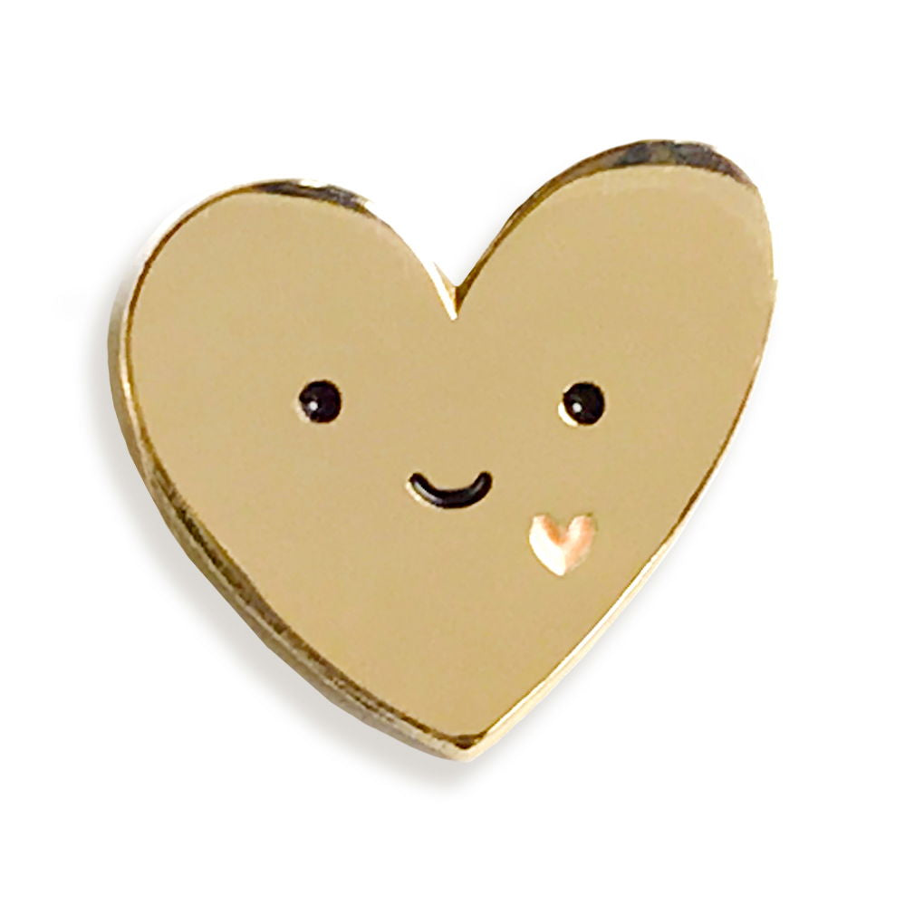 Front of gold Happy Heart enamel pin with happy face and small pink heart.