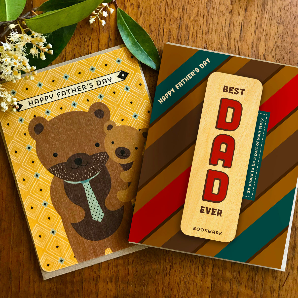 Bear Cub Wood Father's Day Card and Dad Story Bookmark Father's Day Card shown side by side on a wood able. Both are shown with a kraft envelope.