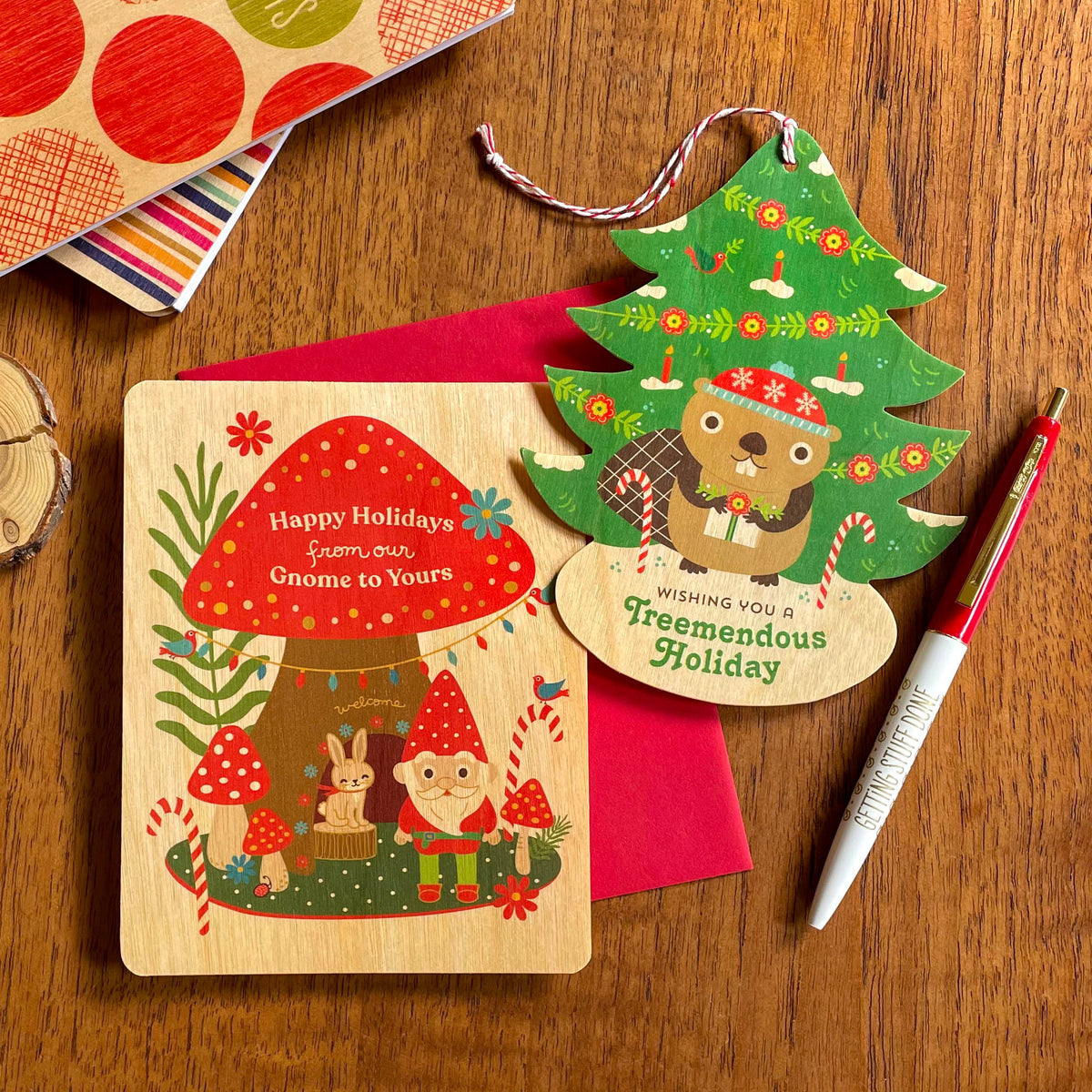 Gnome Wood Holiday Card and Beaver Wood Holiday Ornament Card, side by side on a wood table.