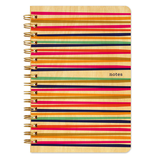 Spiral-bound wood notebook with birch wood covers featuring bold multicolor horizontal stripes in pink, orange, navy, red and teal with small "notes" text.