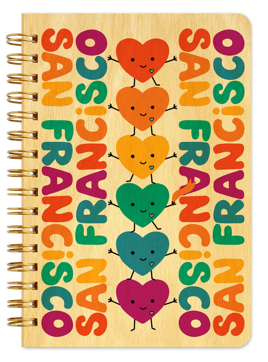 Spiral-bound wood notebook with birch wood covers featuring a stack of smiling rainbow heart characters with arms and legs surrounded by colorful "San Francisco" text.