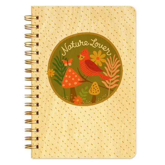 Spiral-bound wood notebook with birch wood covers featuring a red cardinal perched on a branch among mushrooms, flowers and foliage inside a circular "Nature Lover" badge illustration.