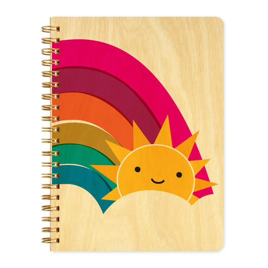 Spiral-bound wood journal with birch wood covers featuring a smiling sun peeking out from behind a bold rainbow in pink, orange, gold and teal.