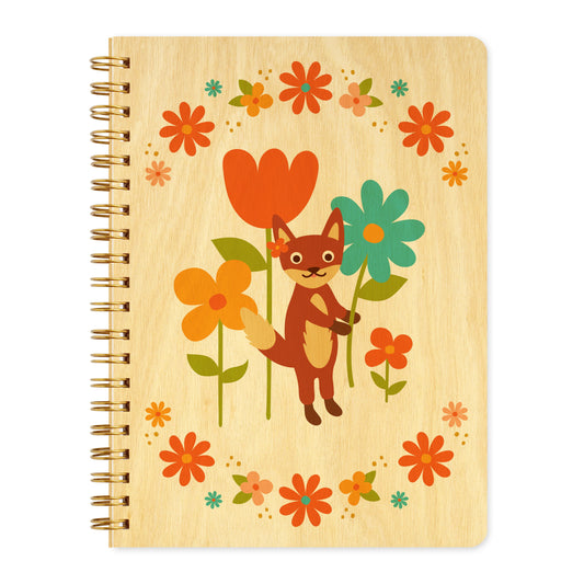 Spiral-bound wood journal with birch wood covers featuring a fox among colorful tulips, daisies and flowers in orange, teal and yellow framed by a floral wreath border.