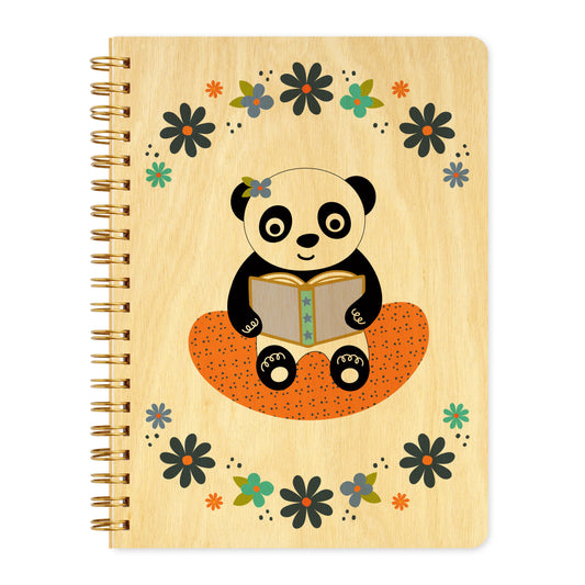 Spiral-bound wood journal with birch wood covers featuring a panda with a purple flower tucked above its ear reading a book on an orange cushion, framed by a purple and aqua floral wreath border.