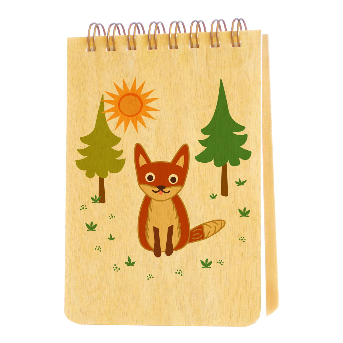 Spiral-bound wood mini notepad with birch wood covers featuring a smiling fox sitting in a sunny forest clearing with pine trees.