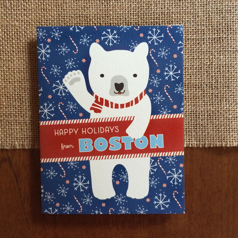 Polar Boston folded paper holiday card featuring a polar bear in a red striped scarf waving against a bold blue background with snowflakes and candy canes and the greeting "Happy Holidays from Boston"