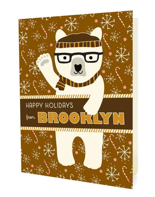 Polar Brooklyn folded paper holiday card featuring a polar bear in black glasses and a brown striped beanie and scarf waving against a warm brown background with snowflakes and candy canes and the greeting "Happy Holidays from Brooklyn"
