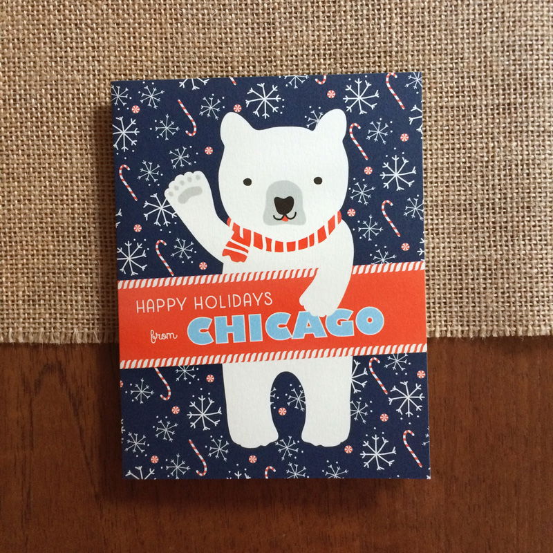 Polar Chicago folded paper holiday card featuring a polar bear in a red striped scarf waving against a navy blue background with snowflakes and candy canes and the greeting "Happy Holidays from Chicago"