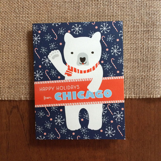 Polar Chicago folded paper holiday card featuring a polar bear in a red striped scarf waving against a navy blue background with snowflakes and candy canes and the greeting "Happy Holidays from Chicago"