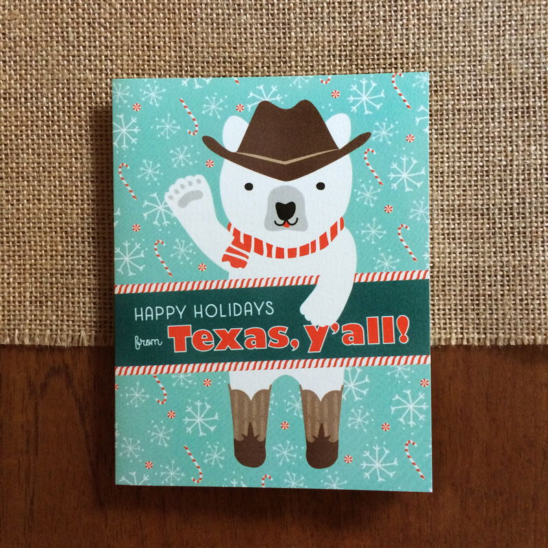 Polar Texas folded paper holiday card featuring a polar bear in a cowboy hat, red striped scarf and cowboy boots waving against an aqua background with snowflakes and candy canes and the greeting "Happy Holidays from Texas, y'all!"